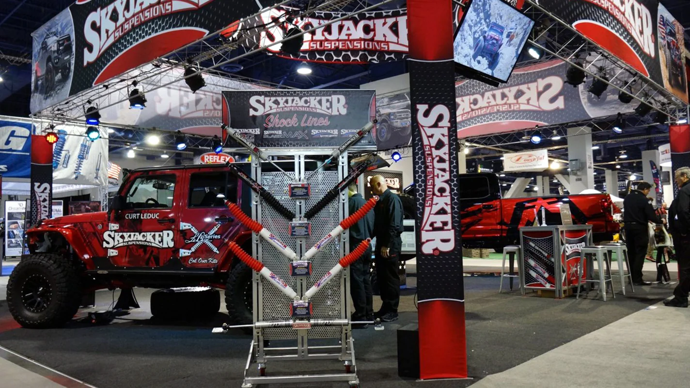 Skyjacker booth interior and product display with red Jeep and suspended exhibit graphics